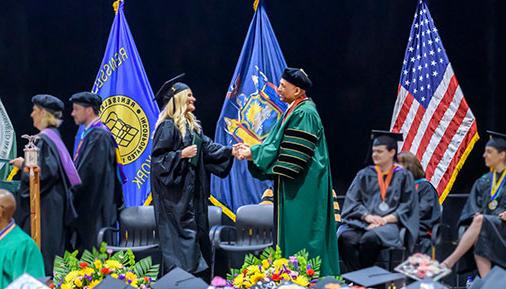 Graduate crossing the stage shaking President Ramsammy's hand